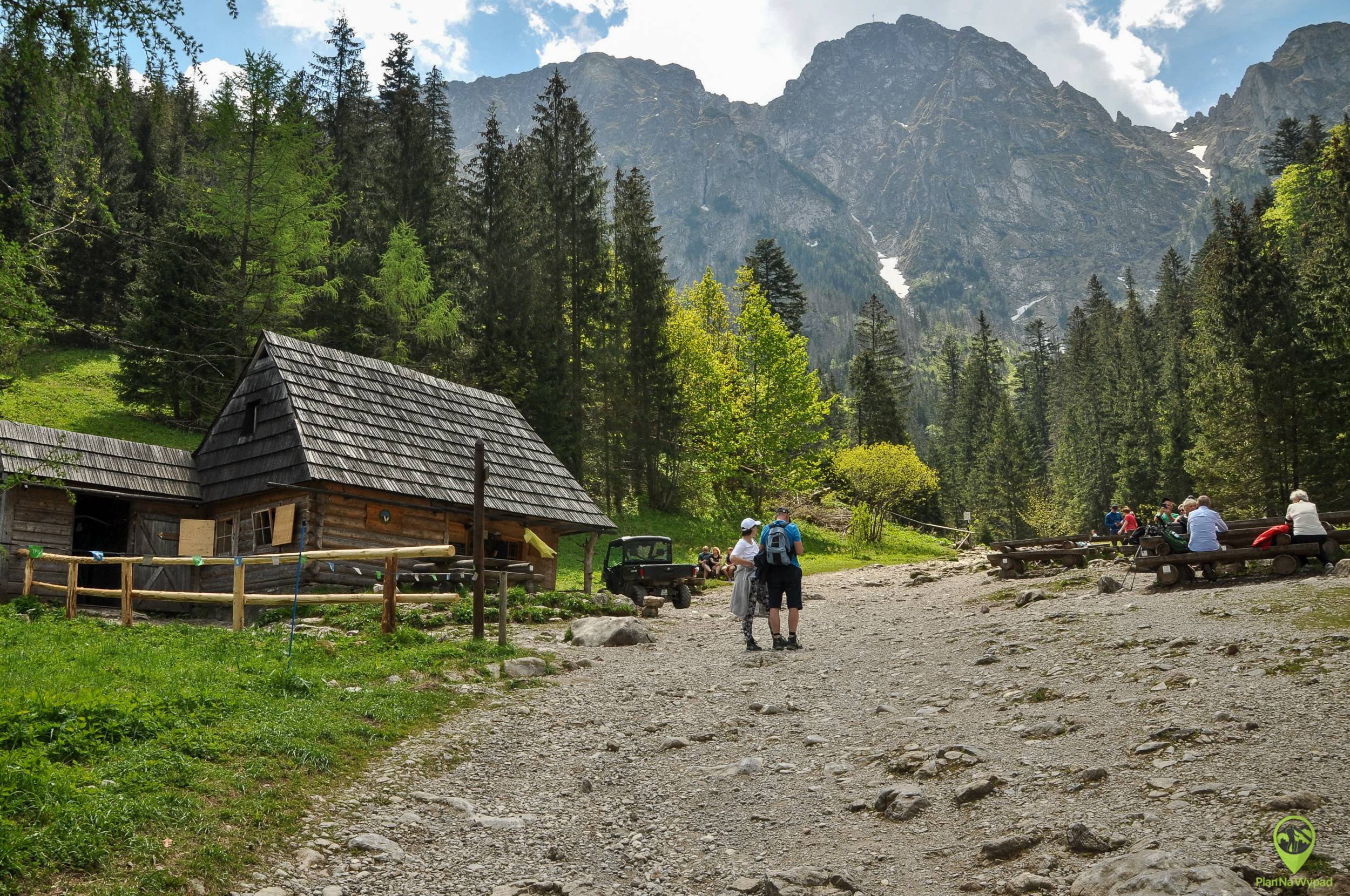 Family walking through Dolina Strążyska valley towards Siklawica waterfall cascading down mountainside