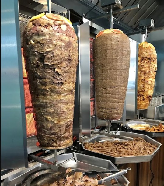 Three vertical doner spits turning behind the counter at Kebab Habibi