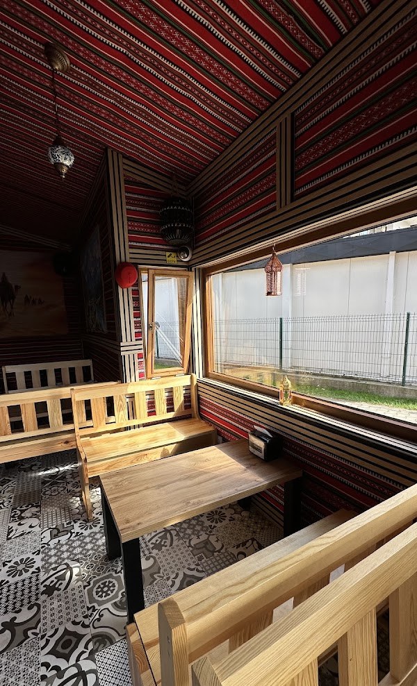 Interior of Kebab Habibi with kilim-patterned walls, lanterns and pine benches