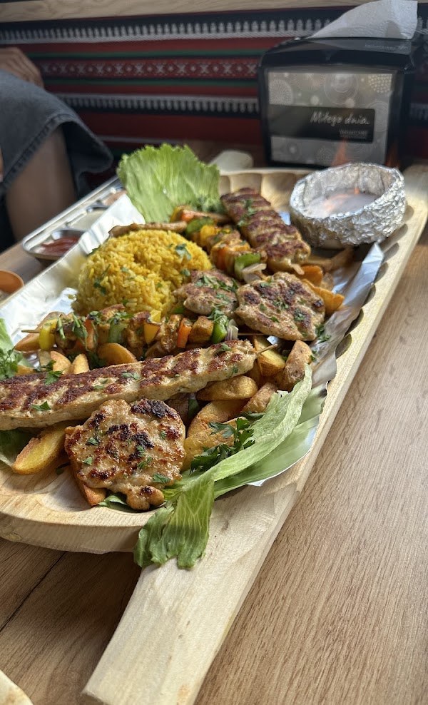 Mixed grill platter at Kebab Habibi with kofta, saffron rice, salad and fries on a wooden board